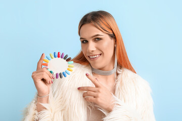 Wall Mural - Young transgender woman with nail polish tips on blue background