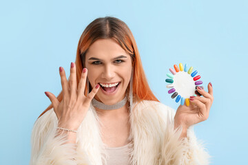 Poster - Happy transgender woman with nail polish tips on blue background