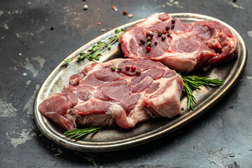 Poster - meat with seasoning. Pieces of raw pork steaks with rosemary and pepper on a dark background. banner, menu, recipe place for text, top view