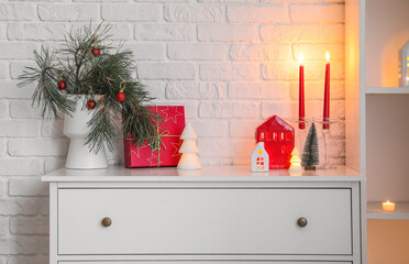 Wall Mural - Vase with Christmas branches, gift and candle holders on chest of drawers near white brick wall