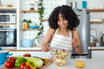 Healthy lifestyle. Good life. Organic food. Vegetables. Close up portrait of happy cute beautiful young woman while she try tasty vegan salad in the kitchen at home.