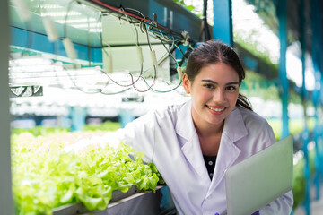 young woman scientist holding laptop computer analyzes and studies research in organic, hydroponic v
