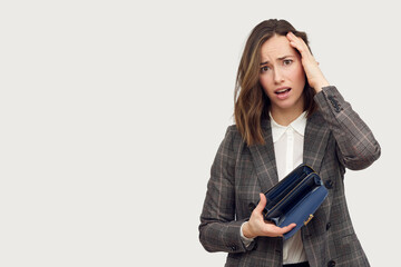 Wall Mural - Young beautiful business woman on white background holding an empty wallet looking frustrated.