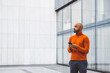 © VisualProduction - Man in orange sweater standing outside with a digital device in his hands
