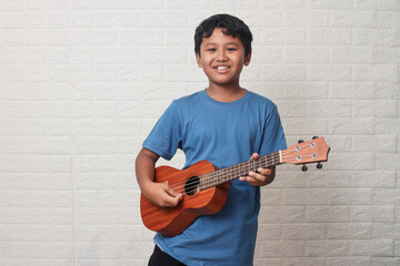 Portrait of Asian little kid playing guitar on white background