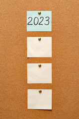 Blank paper notes are pinned to a cork board. Inscription 2023. The concept of detective investigation. Copy space.