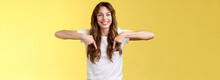 Friendly Cheerful Excited Happy Smiling Girl Long Natural Brunette Haircut Grinning Joyfully Pointing Down Index Fingers Show Friend Great Choice Introduce Promo Advice Click Link Yellow Background