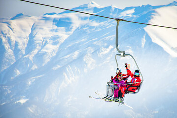 25th january, 2022 - Gudauri, Georgia: caucasian family of three sit on chairlift enjoy views pose on winter ski holidays outdoors. Togetherness xmas holidays and fun