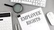 EMPLOYEE RIGHTS written on paper with office tools and keyboard on the grey background