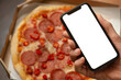 © Berzyk - male hand with phone and pizza on background