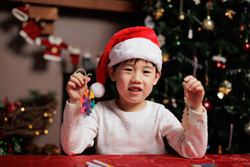 young girl wearing santa hat was making Christmas craft at home