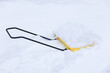 A yellow shovel with snow is lying in a snowdrift. Cleaning tool. Selective focus