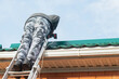 © Ольга Рязанцева - an adult man with his own hands installs snow removals on the roof of his house, preparing the house for a snowy cold winter