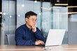 © Liubomir - Serious and thoughtful businessman working inside office sitting at table using laptop at work, mature asian boss in shirt thinking and typing on keyboard.