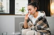 © Serhii - Nasal spray in hand of sick young woman sitting on couch. Allergic rhinitis symptoms and treatment