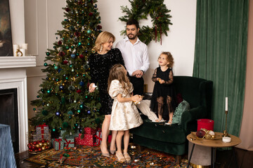 happy family with two daughters playing with confetti at home on Christmas holidays. Christmas tree on background.