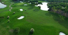 Aerial View Of The Golf Course. Green Manicured Lawn On The Territory Of The Golf Course. Electric Golf Cars Rides On The Lawn, Aerial Shot