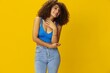 © SHOTPRIME STUDIO - Woman with curly afro hair in a blue t-shirt on. yellow background signs with her hands, look into the camera, smile with teeth and happiness, copy space