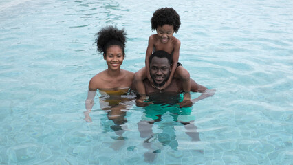 Group of african american family, dad, mother and daughter playing by the swimming pool in summer season. People lifestyle in travel holiday vacation concept.