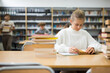 © JackF - Intelligent girl sitting at table and preparing for exams in library.