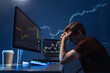 Side view of depressed thoughtful male crypto investor holding head in hands in front of computer with candlestick chart of crypto currency market, failed gaining money, upset with global recession