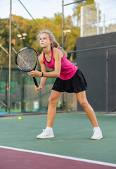 Wall Mural - Young woman in skirt playing tennis on court. Racket sport training outdoors.