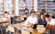 © JackF - Three schoolchildren preparing for lessons in the school library are looking for the necessary information on a laptop, ..discussing topical issues