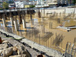 Construction of a monolithic-frame building, unfinished foundation with reinforced concrete columns at a construction site with a flooded pit