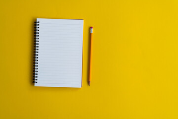 Wall Mural - Blank notebook and a pen on yellow background