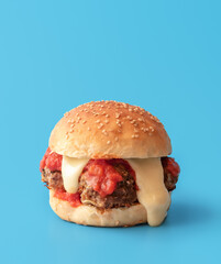 Wall Mural - Meatballs burger with melted cheese, minimalist on a blue background