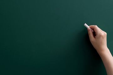 Wall Mural - Hand holding chalk writing on chalkboard