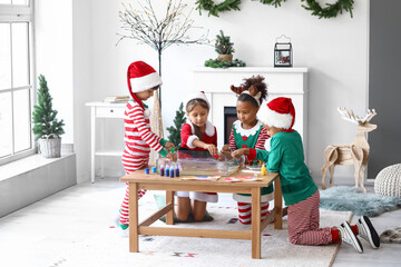 Little children in Christmas costumes pouring paints into water at workshop for Ebru painting