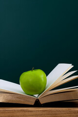 Wall Mural - Green apple on book in front of the blackboard