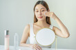 © KMPZZZ - Happy beauty, attractive asian young woman, girl looking reflect in mirror, hand holding cotton pad, applying facial wipe on her face remover makeup, essence or lotion for treatment, skin care routine