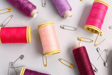 Set Of Colorful Thread Spools And Safety Pins On Light Background, Closeup