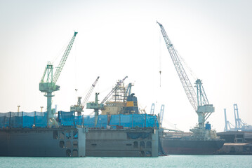 A crane is lifting loads in a shipyard.