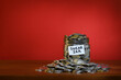 Glass Swear Jar overflowing with Australian coins vibrant red background copy space