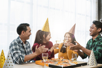 Group of happy colleagues having fun at a new year celebration ahead or business success. Coworkers with diverse ethnicities are toasting wine or champagne glasses at the office party