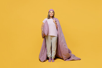 Wall Mural - Full body young fun woman wears purple pyjamas jam sleep eye mask rest relax at home hold in hand blanket duvet pillow go to bed isolated on plain yellow background studio portrait. Night nap concept.