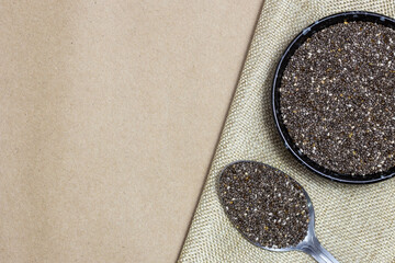 Wall Mural - Healthy and diet food, Chia seeds or superfood in black bowl with spoon on linen cloth