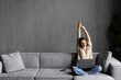 Business woman sitting on sofa with laptop raising her arms above her head stretching after sitting for a long time at work.
