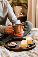 Wall Mural - a caucasian man relaxing at home, lighting candle, drinking coffee in bed