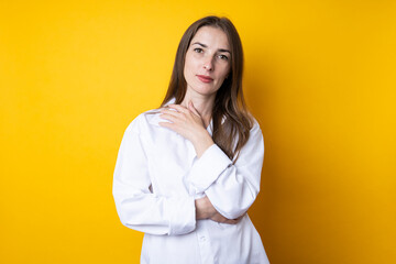 Wall Mural - Cute beautiful young woman in a white shirt on a yellow background