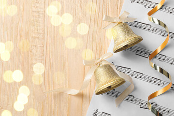 Wall Mural - Golden shiny bells with white bows and music sheet on wooden table, top view and space for text. Christmas decoration