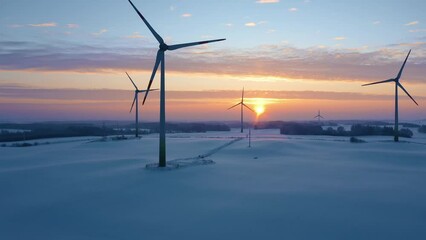 wind turbines at sunrise in snow covered fields. winter wind farm generating green energy