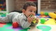 © Krakenimages.com - Adorable hispanic baby sucking car toy lying on floor at kindergarten