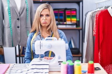 Sticker - Blonde woman dressmaker designer using sew machine depressed and worry for distress, crying angry and afraid. sad expression.