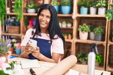 Wall Mural - Middle age hispanic woman florist smiling confident using smartphone at florist