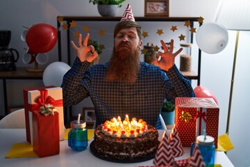 Poster - Caucasian man with long beard celebrating birthday holding big chocolate cake relax and smiling with eyes closed doing meditation gesture with fingers. yoga concept.