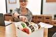 © Krakenimages.com - Young caucasian woman business worker using laptop holding doughnut at office